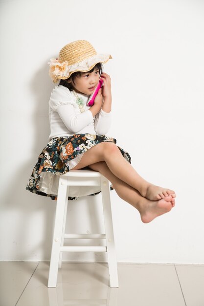 Menina segurando o telefone para falar no telefone com a amiga.