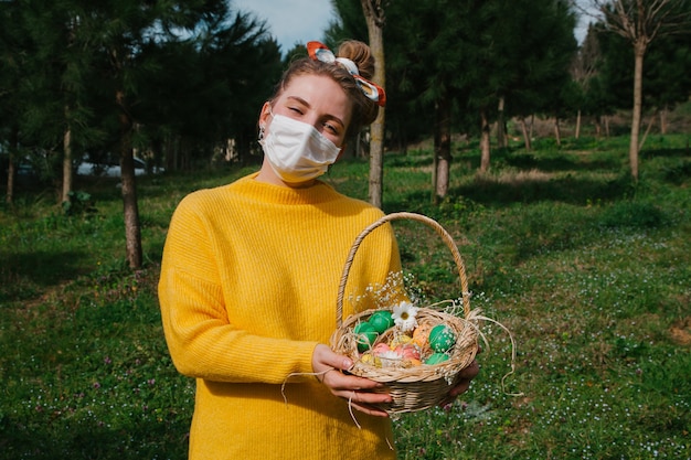 Menina segurando ovos de Páscoa na cesta com flores e doces