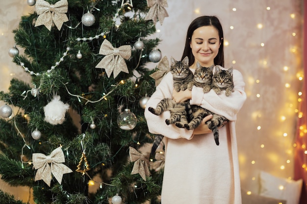 Menina segurando três gatinhos listrados