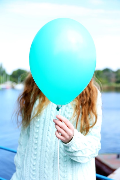 Foto menina segurando um balão perto do rosto