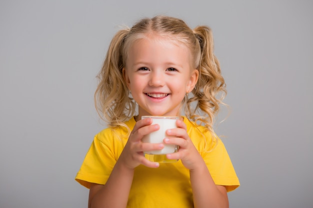 menina, segurando um copo de leite sobre um fundo claro, espaço para texto