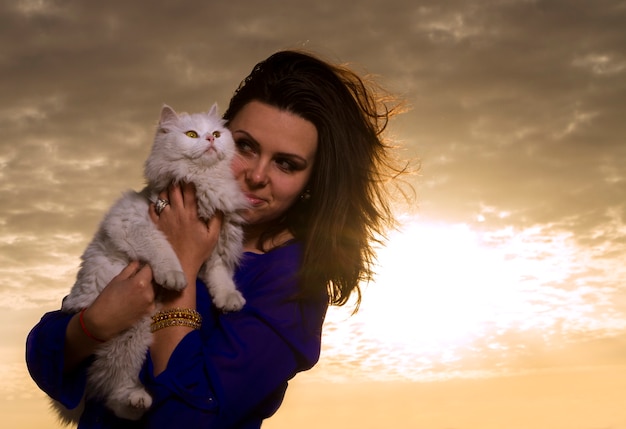 Foto menina segurando um gato branco ao pôr do sol