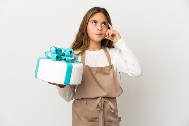 Menina segurando um grande bolo sobre fundo branco isolado, tendo dúvidas e pensando