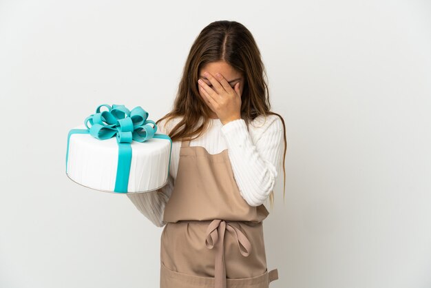 Menina segurando um grande bolo sobre um branco isolado com uma expressão cansada e doente