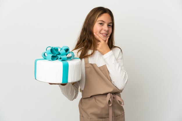 Menina segurando um grande bolo sobre um fundo branco isolado feliz e sorridente