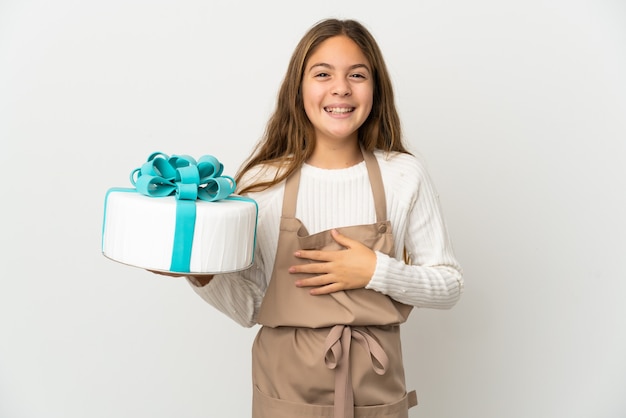 Menina segurando um grande bolo sobre um fundo branco isolado sorrindo muito