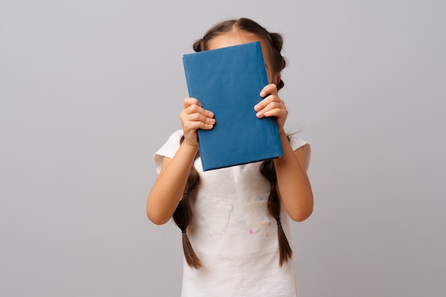 Menina, segurando um livro nas mãos dela