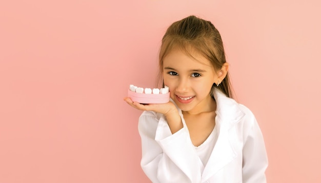 Menina segurando um modelo de mandíbula na mão para demonstrar a escovação adequada dos dentes