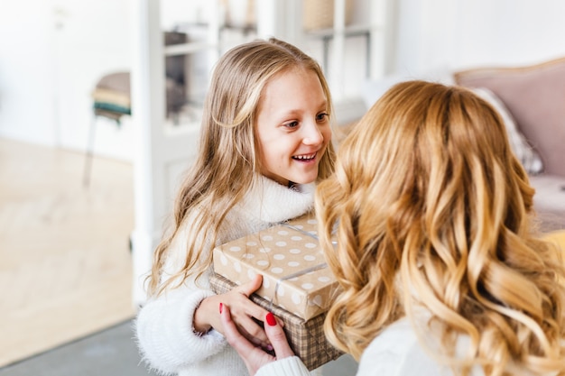 menina segurando um presente e dá para a mãe dela