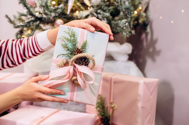 Menina segurando um presente, uma árvore de natal e uma caixa rosa com um presente