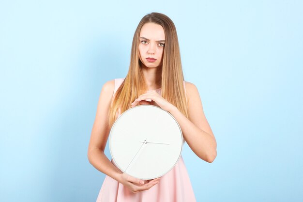 Menina segurando um relógio mecânico em um fundo colorido