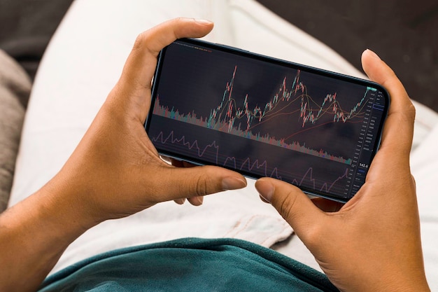 Menina segurando um smartphone com gráfico do mercado financeiro de ações Bolsa de Valores