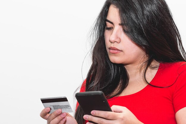 Menina segurando um telefone e um cartão de crédito ao fazer uma transação online