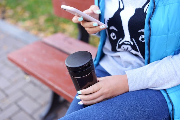 Menina, segurando, um, telefone, e, um, xícara café cappuccino quente