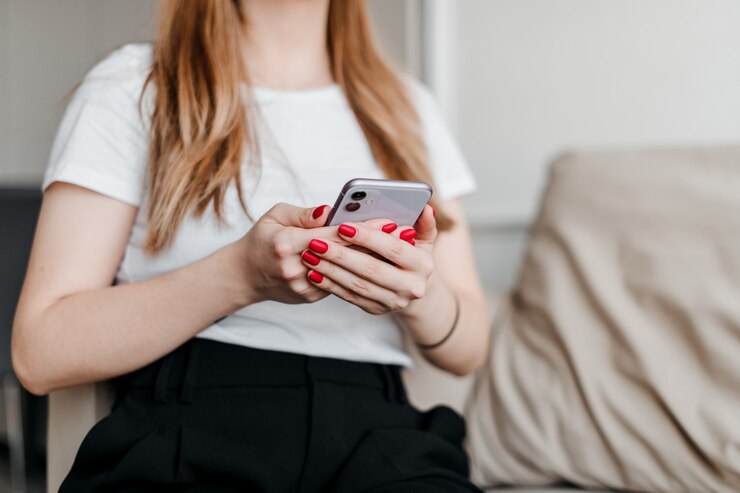 Foto menina, segurando um telefone, sentado em um sofá em um apartamento moderno e brilhante