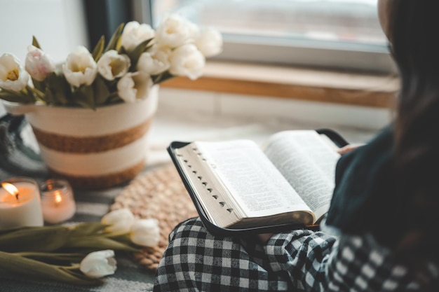 Menina segurando uma bíblia aberta em suas mãos conceito de estudo em casa