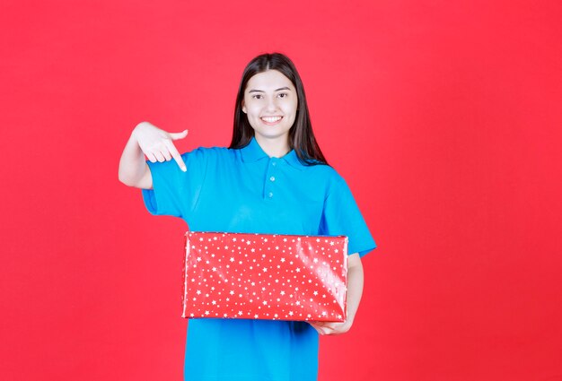 Menina segurando uma caixa de presente vermelha com pontos brancos nela