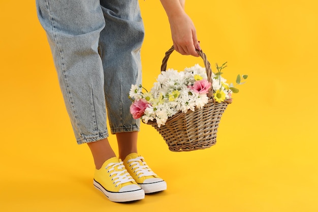 Menina segurando uma cesta de flores sobre fundo amarelo