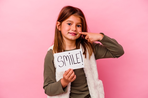 Menina segurando uma faixa de sorriso no fundo rosa