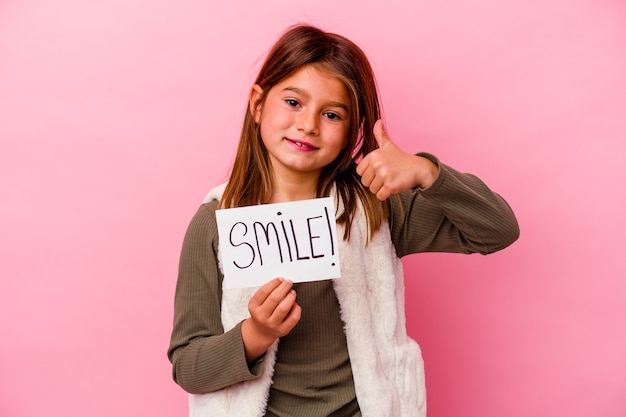 Menina segurando uma faixa de sorriso no fundo rosa