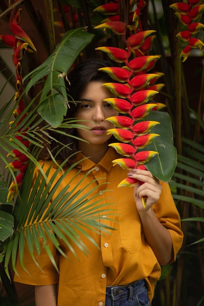 Foto menina segurando uma flor exótica entre arbustos