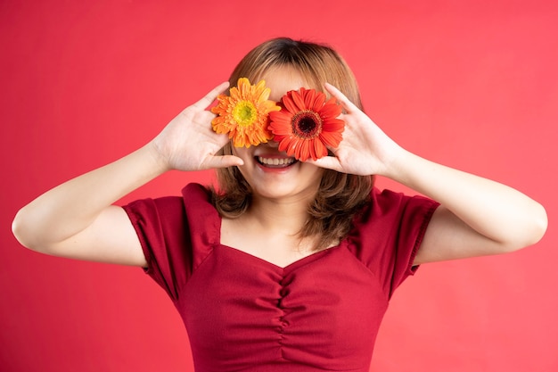 Foto menina segurando uma flor vermelha e amarela sobre os olhos