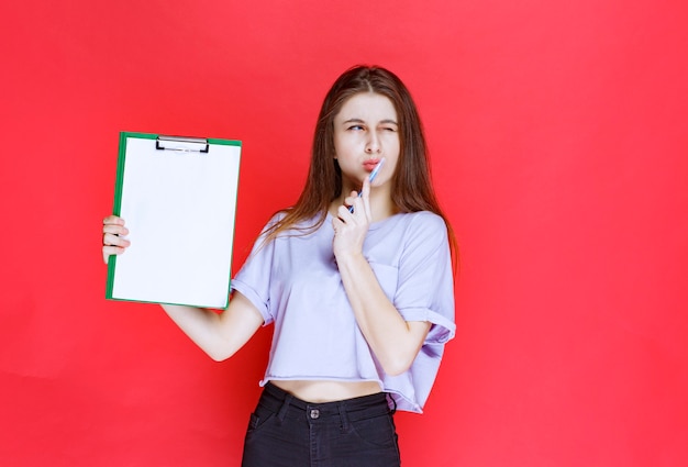 Menina segurando uma folha de relatório em branco e pensando.