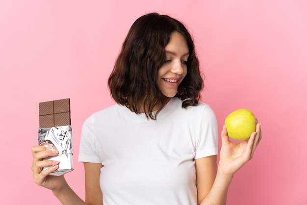 Menina segurando uma maçã e um chocolate