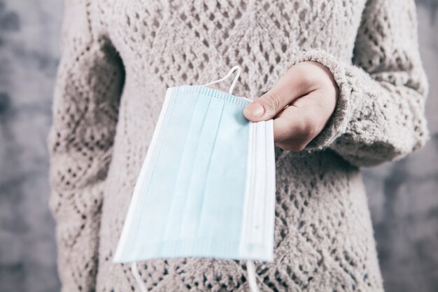 Menina segurando uma máscara médica na mão