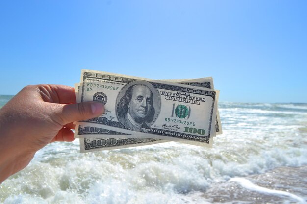 Menina segurando uma nota de dinheiro de 300 dólares no fundo das ondas do mar