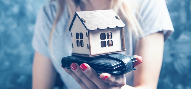 Menina segurando uma pequena casa na mão