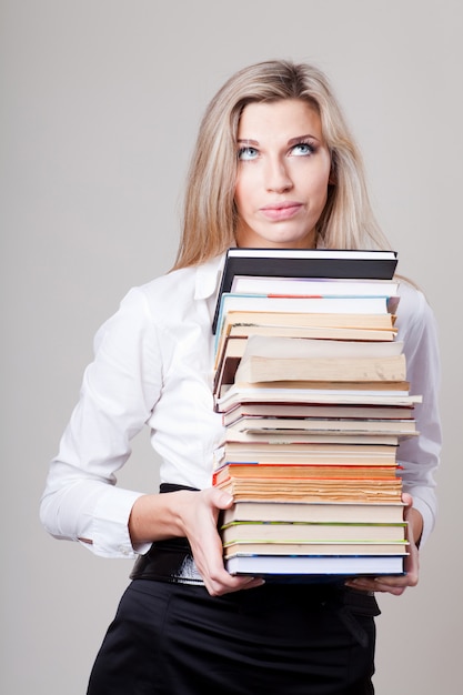 Menina segurando uma pilha de livros