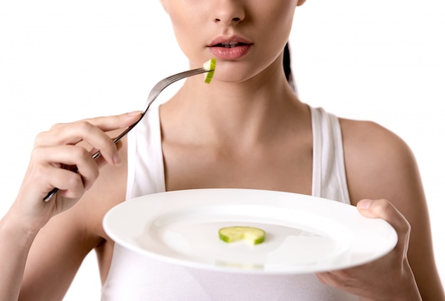 Menina segurando uma placa com uma fatia de pepino. Conceito de dieta.