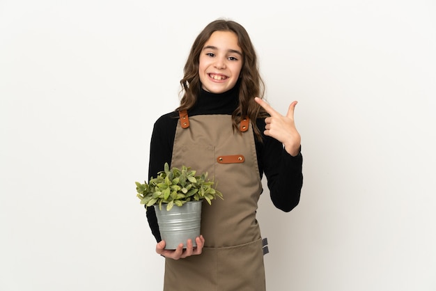 Menina segurando uma planta isolada no fundo branco fazendo um gesto de polegar para cima