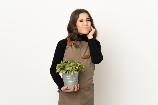 Menina segurando uma planta isolada no fundo branco frustrada e cobrindo as orelhas