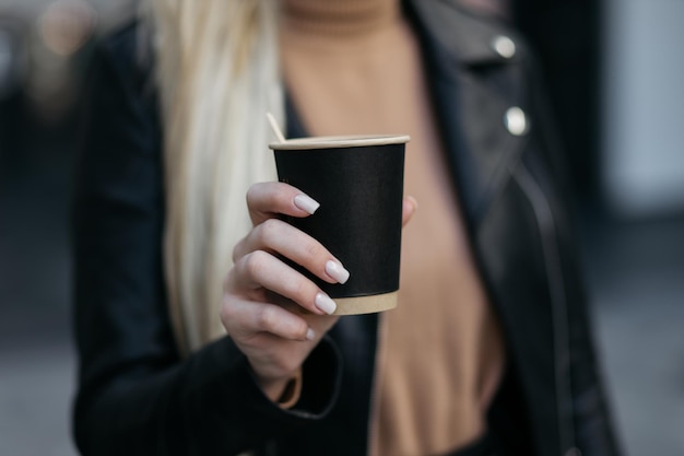 Foto menina segurando uma xícara de papelão xícara de café de papel em uma mão de mulher no fundo da loja bebida quente mão segurando uma xícara de café de papel xícara de café de papel