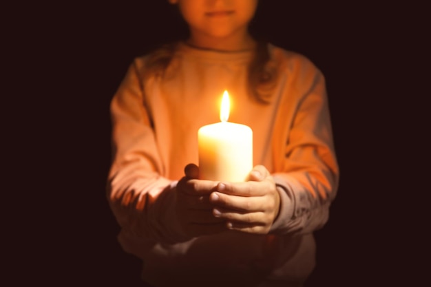 Menina segurando vela acesa na escuridão