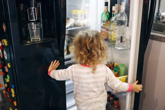 Menina sem rosto, olhando para dentro da geladeira