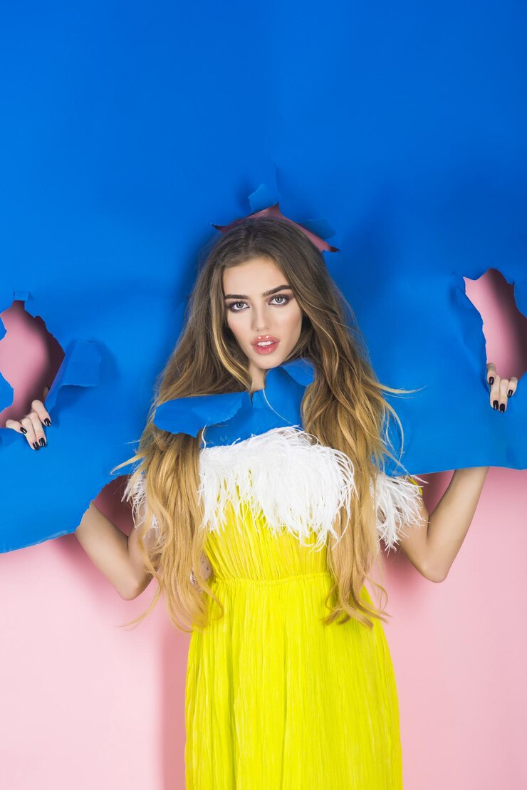 Foto menina sensual olhando pelo buraco no papel azul linda garota no vestido amarelo passando as mãos