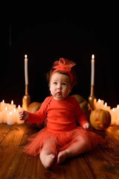 Menina senta-se em um fundo de abóboras Jack e velas em um fundo preto.