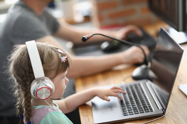 Menina senta-se no laptop em fones de ouvido com microfone ao lado do homem