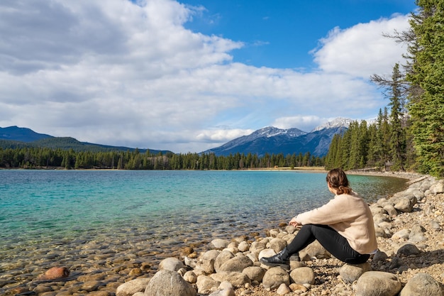 Menina sentada à beira do lago apreciando a paisagem natural Horário de verão no lago Annette