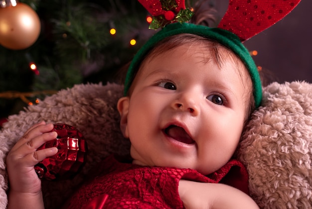 Menina sentada ao lado da árvore de Natal