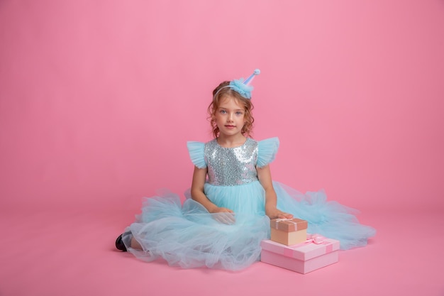 menina sentada comemorando aniversário em fundo rosa, lindo vestido de princesa