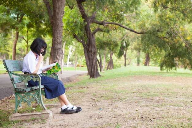 Menina sentada e lendo um livro.