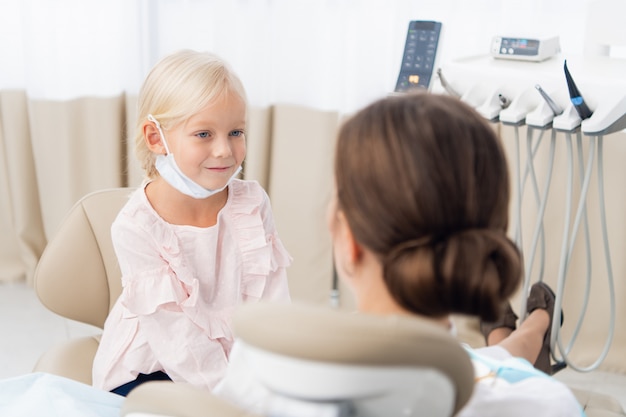 Menina sentada e sorrindo no consultório do dentista.