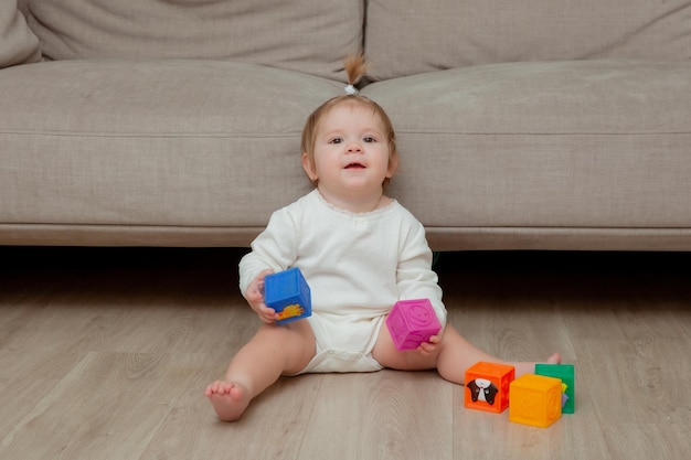 Menina sentada em casa no chão jogando cubos de desenvolvimento infantil