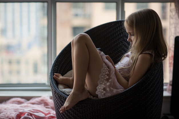 Foto menina sentada em casa usando o celular