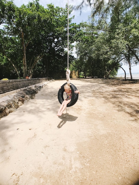 Foto menina sentada em um baloiço no playground