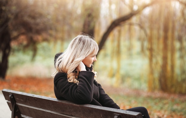 Menina sentada em um banco de parque em um dia de outono